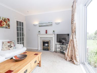 A living room with a sofa, coffee table, and television at Mayflower View in Dawlish