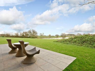 A patio area with a table and chairs overlooking a lake at Brayton in Aspatria