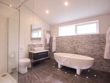 A bathroom with a bathtub, toilet, sink and towel rack at Brayton in Aspatria