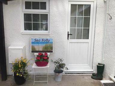 An entrance with a door, window, planter, and sign at Sea Folly in Porthcawl