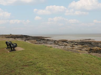 A bench beside the rocks and ocean at Sea Folly in Porthcawl