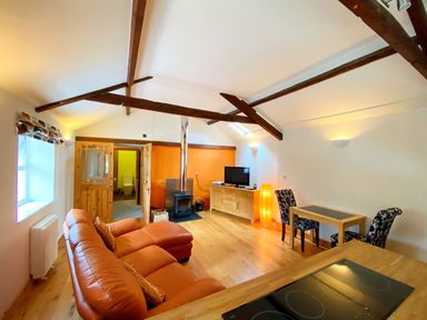 A living room with a sofa, television, and wooden furniture at Upper Stable - The Stables Apartments at Meadfoot Bay, Torquay