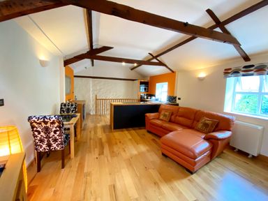 A living room with a sofa and dining area at Upper Stable - The Stables Apartments at Meadfoot Bay, Torquay