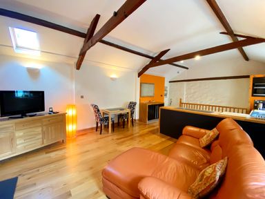 A living room with a television and dining area at Upper Stable - The Stables Apartments at Meadfoot Bay, Torquay