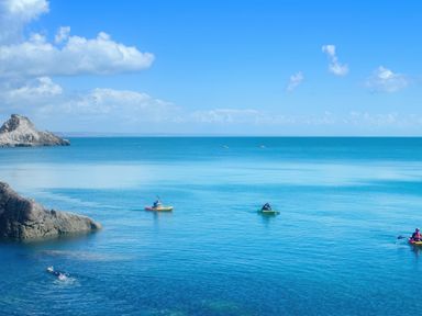 A view of kayaks on an ocean with a rocky coastline at Muntham - Studio Apartment 7 in Torquay