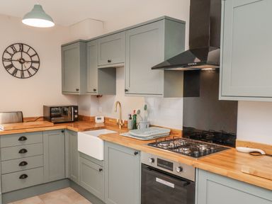 A kitchen with grey cabinets and wooden countertops at Starlight Cottage