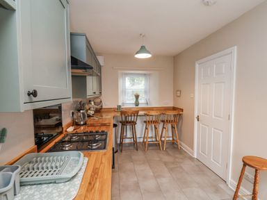 A kitchen with bar counter and stools at Starlight Cottage 