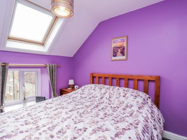 A bedroom with a bed and window at Starlight Cottage