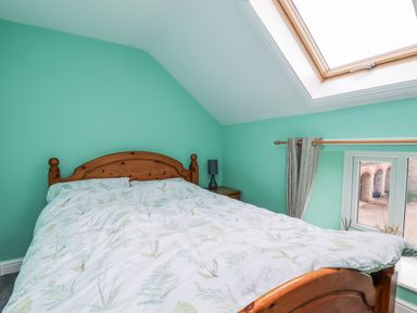 A bedroom with a bed and window at Starlight Cottage
