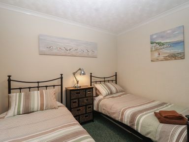 A bedroom with two beds and paintings on the wall at Willow Lodge near Liskeard