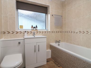 A bathroom with a bathtub and washbasin at Willow Lodge near Liskeard