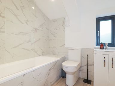 A bathroom with a bathtub, toilet, sink, and window at Barn 5