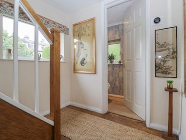 A hallway with a staircase and framed artwork at Apple Byrd in Kendal