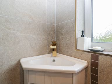 A bathroom with a corner sink and faucet at Apple Byrd in Kendal