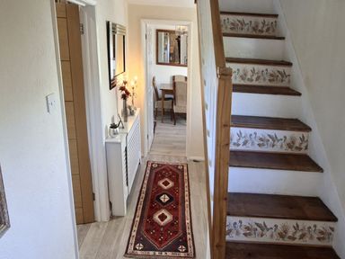 A hallway with a staircase and a console table at Apple Byrd in Kendal