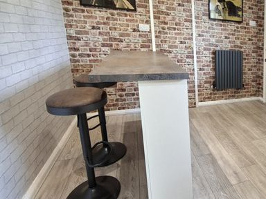 A kitchen with a countertop and bar stools at Apple Byrd in Kendal