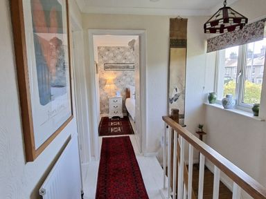 A hallway leading to a bedroom with a lamp and dresser at Apple Byrd in Kendal