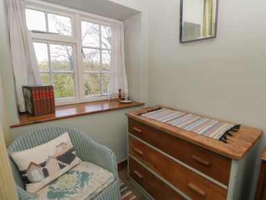 A room with a window, a chest of drawers, and a chair at Tyn Y Fron in Brynherbert near Llanrhystud