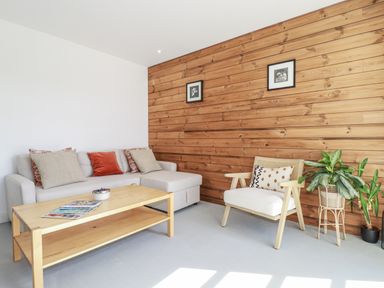 A living room with a sofa and coffee table at Teach Tra East, Perranporth