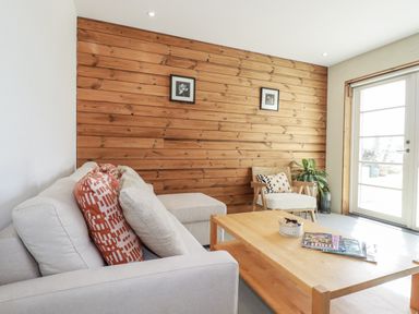 A living room with a sofa and coffee table at Teach Tra East in Perranporth