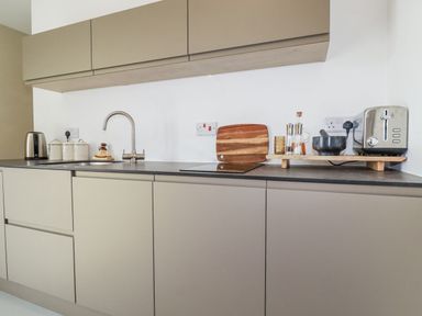 A kitchen with cabinets, sink, kettle, toaster and coffee maker at Teach Tra East in Perranporth
