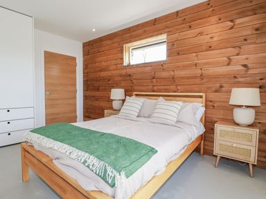 A bedroom with a bed and bedside tables at Teach Tra East in Perranporth