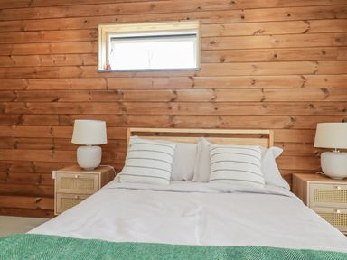 A bedroom with a bed and lamps at Teach Tra East in Perranporth