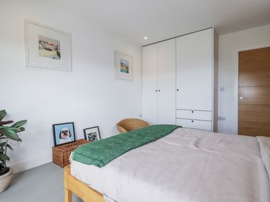 A bedroom with a bed and wardrobe at Teach Tra East in Perranporth