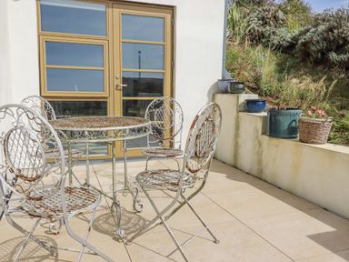 A patio with a table and chairs at Teach Tra East, Perranporth
