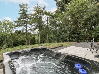 A hot tub and seating area in an outdoor space at Oak View in Rhayader