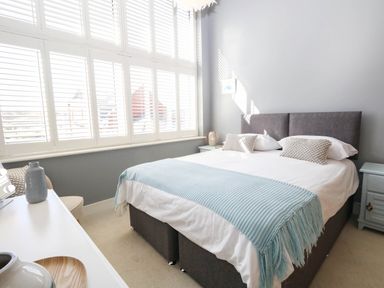 A bedroom with a bed and window shutters at Harbour Heights in Weymouth