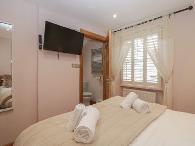A bedroom with a bed, television, and bathroom door at Park View, Ambleside