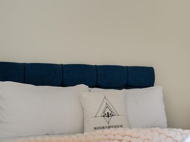 A bed with a blue headboard and white pillows at Manor Farm House in Merton near Bicester