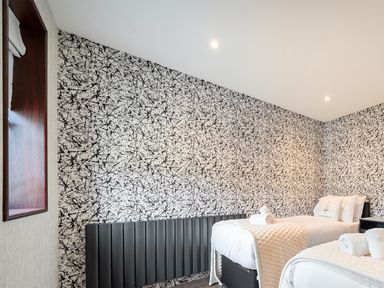 A bedroom with two beds and a decorative wall at Manor Farm House in Merton near Bicester