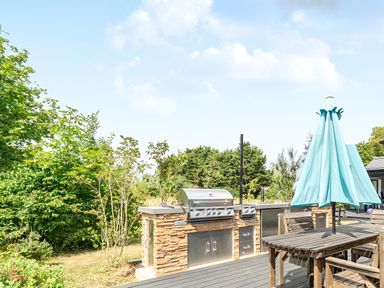 An outdoor kitchen with a grill and table at Manor Farm House in Merton near Bicester