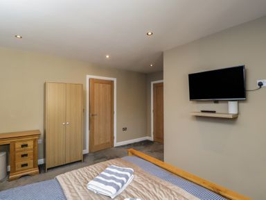 A bedroom with a wardrobe and television at Willow Cottage in Whiteparish