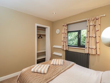 A bedroom with a bed and wardrobe at Willow Cottage in Whiteparish