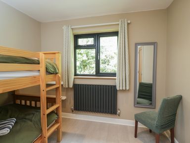 A bedroom with bunk bed, mirror, and window at Willow Cottage in Whiteparish