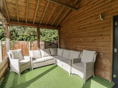 A snug area with a sofa and wooden walls at Willow Cottage in Whiteparish