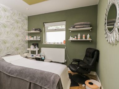 A spa room with a massage table and shelves of products at Willow Cottage in Whiteparish