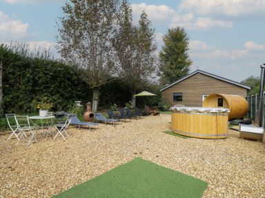A garden area with lounge chairs and a barrel at Willow Cottage in Whiteparish