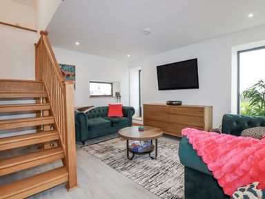 A living room with a staircase, couch and coffee table at Barn 2