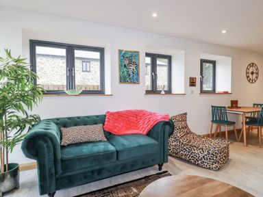 A living room with a green sofa and a dining table at Barn 2 