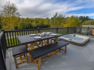 A table and hot tub on a deck at Lakewood Retreat in Woodhall Spa