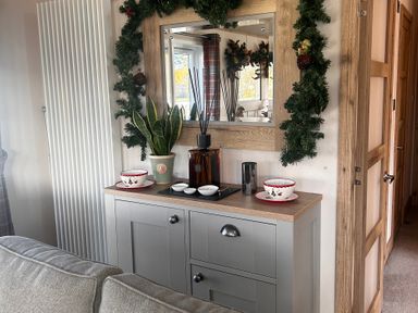A living room with a sideboard and houseplants at Lakewood Retreat in Woodhall Spa