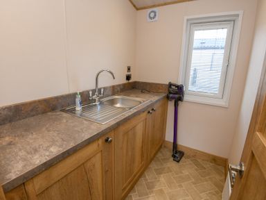 A utility room with a sink and storage cabinets at Lakewood Retreat in Woodhall Spa