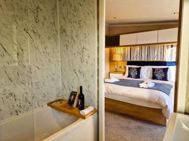 A bathroom with a bathtub and a bedroom with a bed at Hotchkin Lodge in Woodhall Spa