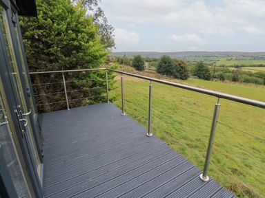 An outdoor deck area with railing and view of hills at John's Folly
