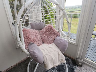 A hanging chair with cushions in a snug at John's Folly