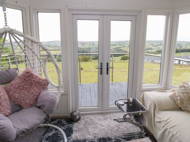 A sunroom with a hanging chair and a couch at John's Folly